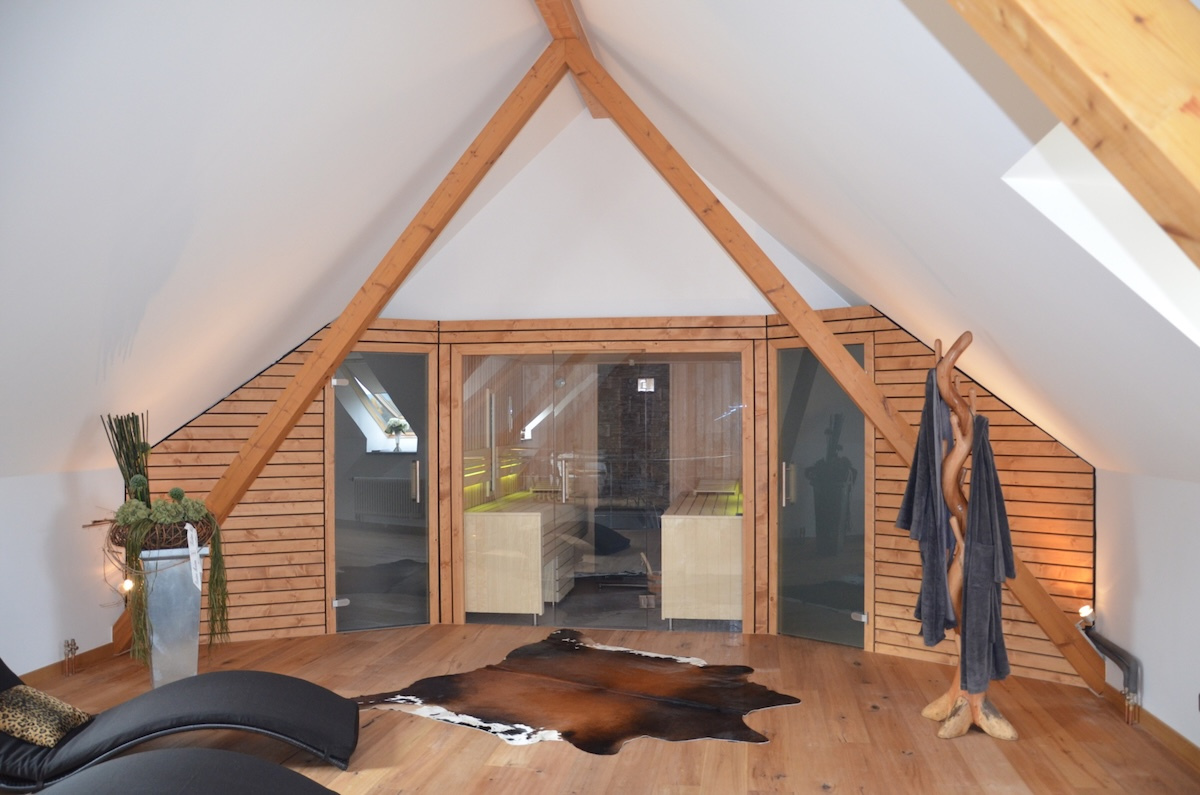 Mittig Sauna, an beiden Seiten durch Nebenräume erweitert. Ensemble eingebaut unter einem Satteldach.